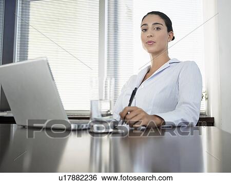 Businesswoman sitting by laptop computer (portrait, low angle view) View Large Photo Image Stock Photograph - Businesswoman sitting by laptop computer (portrait, low angle view). Fotosearch