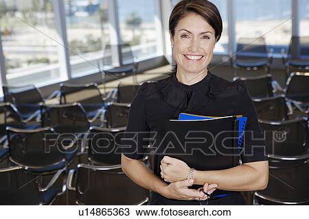 Stock Image - Mature woman in lecture theater (portrait). Fotosearch