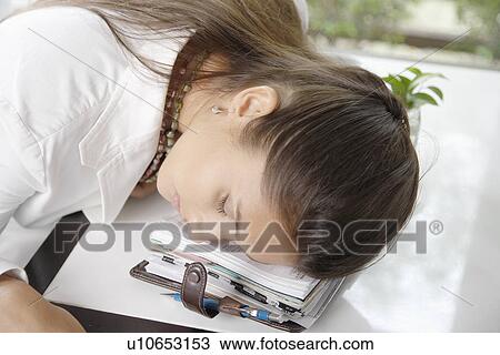 Stock Image - Young businesswoman sleeping on organizer. Fotosearch