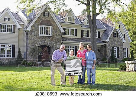 Stock Image - Family of four standing by sign near house, Chatham, New Jersey, USA. Fotosearch
