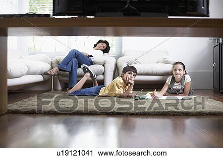 Stock Image - Mother and two children watching TV (low angle view). Fotosearch