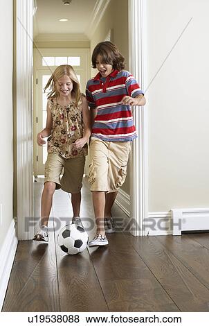 Sister and brother playing soccer indoors View Large Photo Image Stock Photo - Sister and brother playing soccer indoors. Fotosearch
