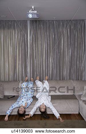 Stock Image - Sister and brother watching TV upside down. Fotosearch