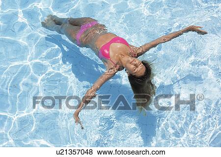 Mid adult woman floating in swimming pool (high angle view) View Large Photo Image Stock Photo - Mid adult woman floating in swimming pool (high angle view). Fotosearch