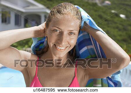 Stock Photography - Mid adult woman in bikini drying hair. Fotosearch
