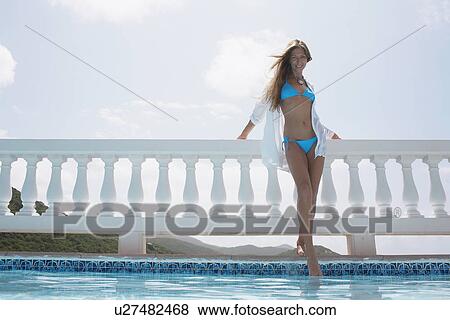 Mid adult woman in bikini standing by fence (low angle view) View Large Photo Image Stock Photo - Mid adult woman in bikini standing by fence (low angle view). Fotosearch