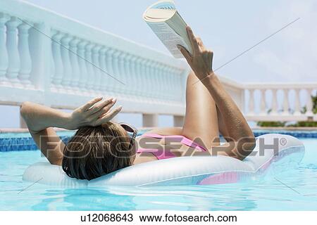 Mid adult woman reading book on pool raft View Large Photo Image Stock Image - Mid adult woman reading book on pool raft. Fotosearch