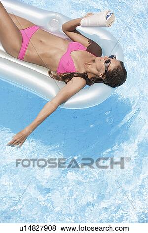 Mid adult woman reading book on pool raft View Large Photo Image Stock Photo - Mid adult woman reading book on pool raft. Fotosearch