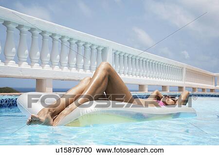 Stock Image - Woman lying on pool raft. Fotosearch