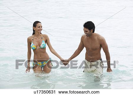 Young couple holding hands and walking in ocean (high angle view) View Large Photo Image Stock Image - Young couple holding hands and walking in ocean (high angle view). Fotosearch