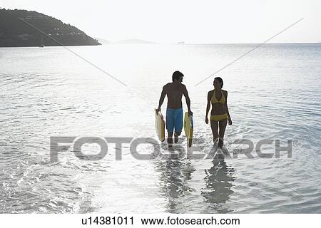 Young couple with bodyboards walking in ocean, St. John, US Virgin Islands, USA View Large Photo Image Stock Image - Young couple with bodyboards walking in ocean, St. John, US Virgin Islands, USA. Fotosearch