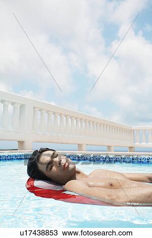 Young man lying on air mattress in swimming pool View Large Photo Image Stock Image - Young man lying on air mattress in swimming pool. Fotosearch