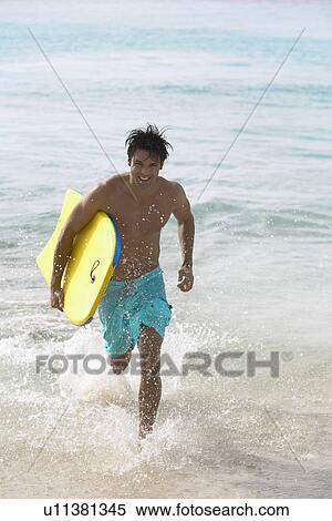 Young man with bodyboard running in water View Large Photo Image Stock Photography - Young man with bodyboard running in water. Fotosearch