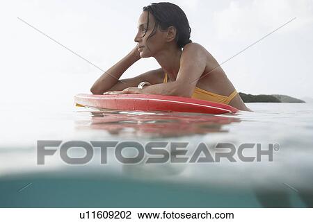 Young woman looking at view on bodyboard (surface level) View Large Photo Image Stock Image - Young woman looking at view on bodyboard (surface level). Fotosearch