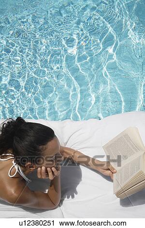 Young woman reading book by pool View Large Photo Image Stock Image - Young woman reading book by pool. Fotosearch