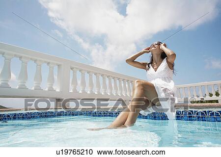 Young woman sitting by pool (low angle view) View Large Photo Image Stock Image - Young woman sitting by pool (low angle view). Fotosearch