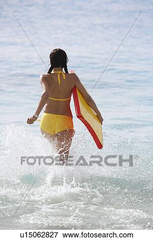 Young woman with bodyboard running in ocean (rear view) View Large Photo Image Stock Photo - Young woman with bodyboard running in ocean (rear view). Fotosearch