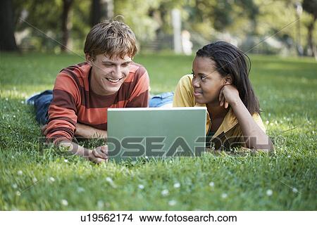 Teenage couple using laptop in park View Large Photo Image Picture - Teenage couple using laptop in park. Fotosearch