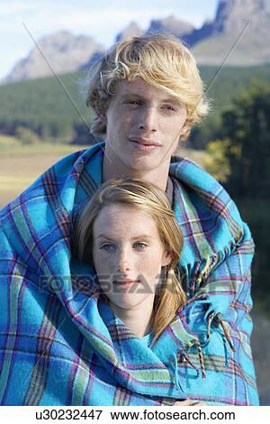 Stock Photo - Teenage couple wrapped in blanket. Fotosearch