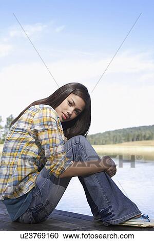 Stock Image - Teenage girl by lake (portrait). Fotosearch