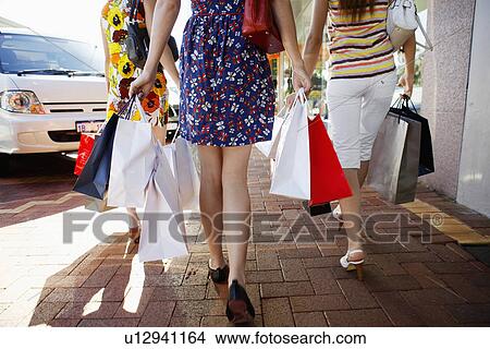 Picture - Teenage girls carrying shopping bags (rear view, low section). Fotosearch
