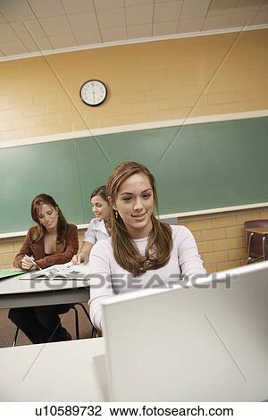 Stock Image - Three female students studying in classrooms. Fotosearch
