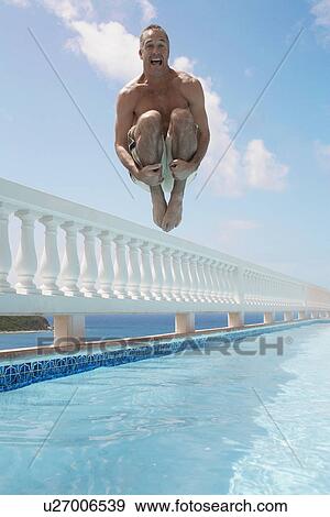 Mid adult man jumping into swimming pool View Large Photo Image Stock Photo - Mid adult man jumping into swimming pool. Fotosearch
