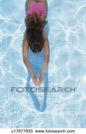 Stock Image - Mid adult woman diving in swimming pool (high angle view). Fotosearch