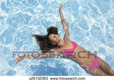 Mid adult woman floating in swimming pool (high angle view) View Large Photo Image Stock Image - Mid adult woman floating in swimming pool (high angle view). Fotosearch