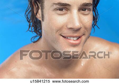 Stock Photography - Young man in water smiling (portrait). Fotosearch