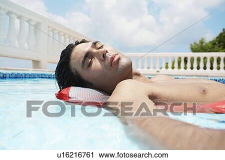 Young man lying on air mattress in swimming pool View Large Photo Image Stock Image - Young man lying on air mattress in swimming pool. Fotosearch