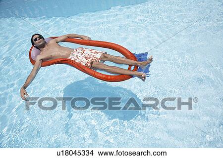 Young man lying on pool raft View Large Photo Image Picture - Young man lying on pool raft. Fotosearch