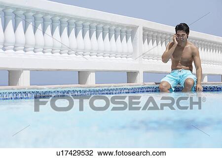 Young man on phone by pool View Large Photo Image Stock Image - Young man on phone by pool. Fotosearch