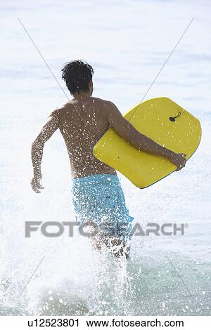 Young man with bodyboard running in water (rear view) View Large Photo Image Stock Image - Young man with bodyboard running in water (rear view). Fotosearch