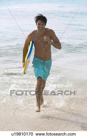 Young man with bodyboard running in water View Large Photo Image Stock Image - Young man with bodyboard running in water. Fotosearch