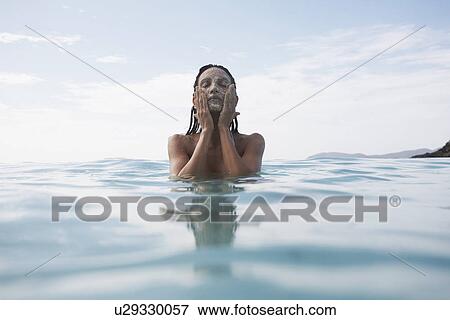 Young woman applying mud mask in water View Large Photo Image Stock Photo - Young woman applying mud mask in water. Fotosearch