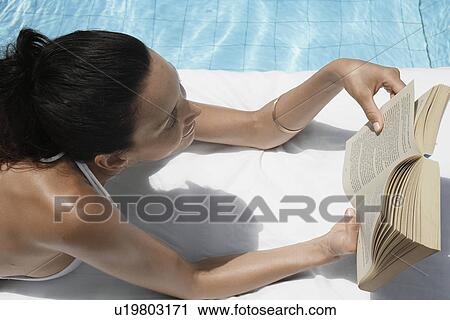 Young woman reading book by pool View Large Photo Image Stock Image - Young woman reading book by pool. Fotosearch