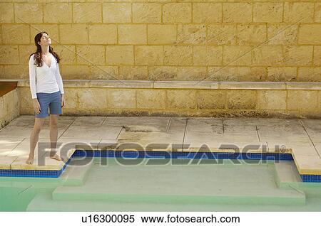 Young woman standing in sun by swimming pool View Large Photo Image Stock Photography - Young woman standing in sun by swimming pool. Fotosearch