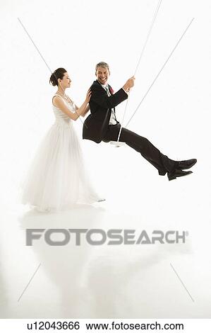 Bride pushing groom in swing set View Large Photo Image Stock Photograph - Bride pushing groom in swing set. Fotosearch