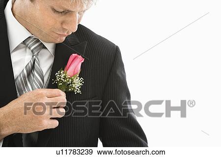 Stock Photo - Caucasian groom adjusting boutonniere.. Fotosearch