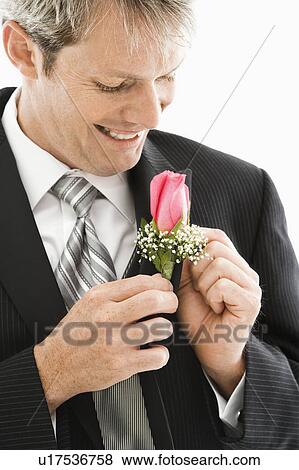 Caucasian groom adjusting boutonniere. View Large Photo Image Stock Photo - Caucasian groom adjusting boutonniere.. Fotosearch