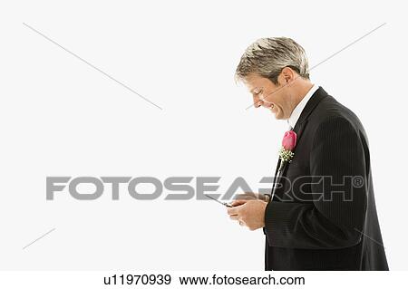 Stock Photo - Caucasian groom texting on cellphone.. Fotosearch