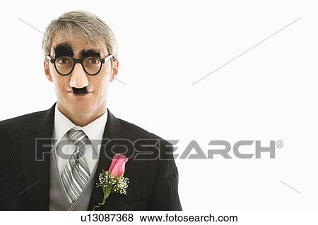 Stock Photo - Caucasian groom wearing groucho glasses making eye contact.. Fotosearch