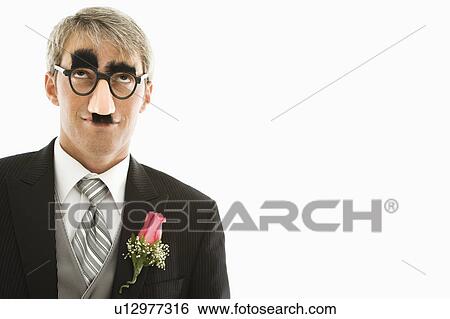 Stock Photograph - Caucasian groom wearing groucho glasses looking up.. Fotosearch