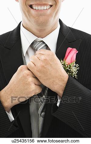 Stock Photograph - Close up of groom adjusting his tie. Fotosearch