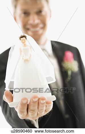 Groom holding out bride figurine in palm of his hand View Large Photo Image Stock Image - Groom holding out bride figurine in palm of his hand. Fotosearch