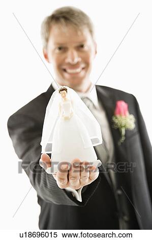 Stock Photography - Groom holding out bride figurine in palm of his hand. Fotosearch