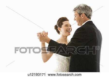 Stock Image - Portrait of Caucasian groom and Asian bride dancing.. Fotosearch