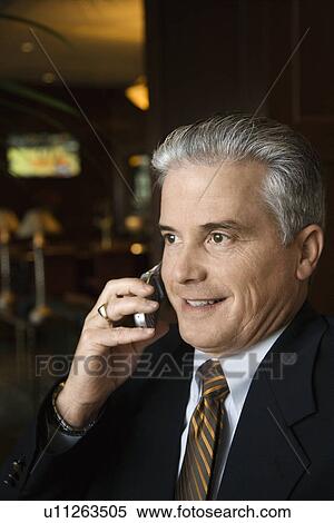 Adult male businessman talking on cell phone in hotel lobby. View Large Photo Image Stock Photography - Adult male businessman talking on cell phone in hotel lobby.. Fotosearch