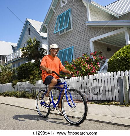 Bicycling down street next to homes and fence View Large Photo Image Stock Photo - Bicycling down street next to homes and fence. Fotosearch